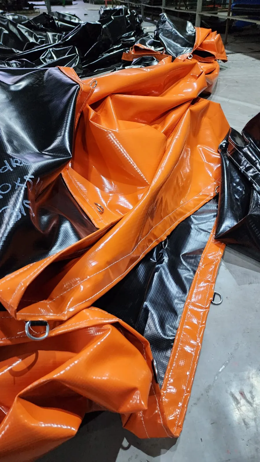 Lonas vinílicas de PVC laranja e preta produzidas pela Lona Mais para cobertura de cargas